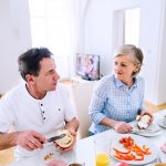 Senior man and woman having breakfast. Sunny morning.