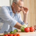 Handsome mature man wearing glasses cooking salad