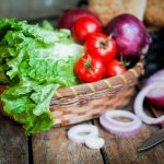 Fresh vegetables in the basket on wooden background